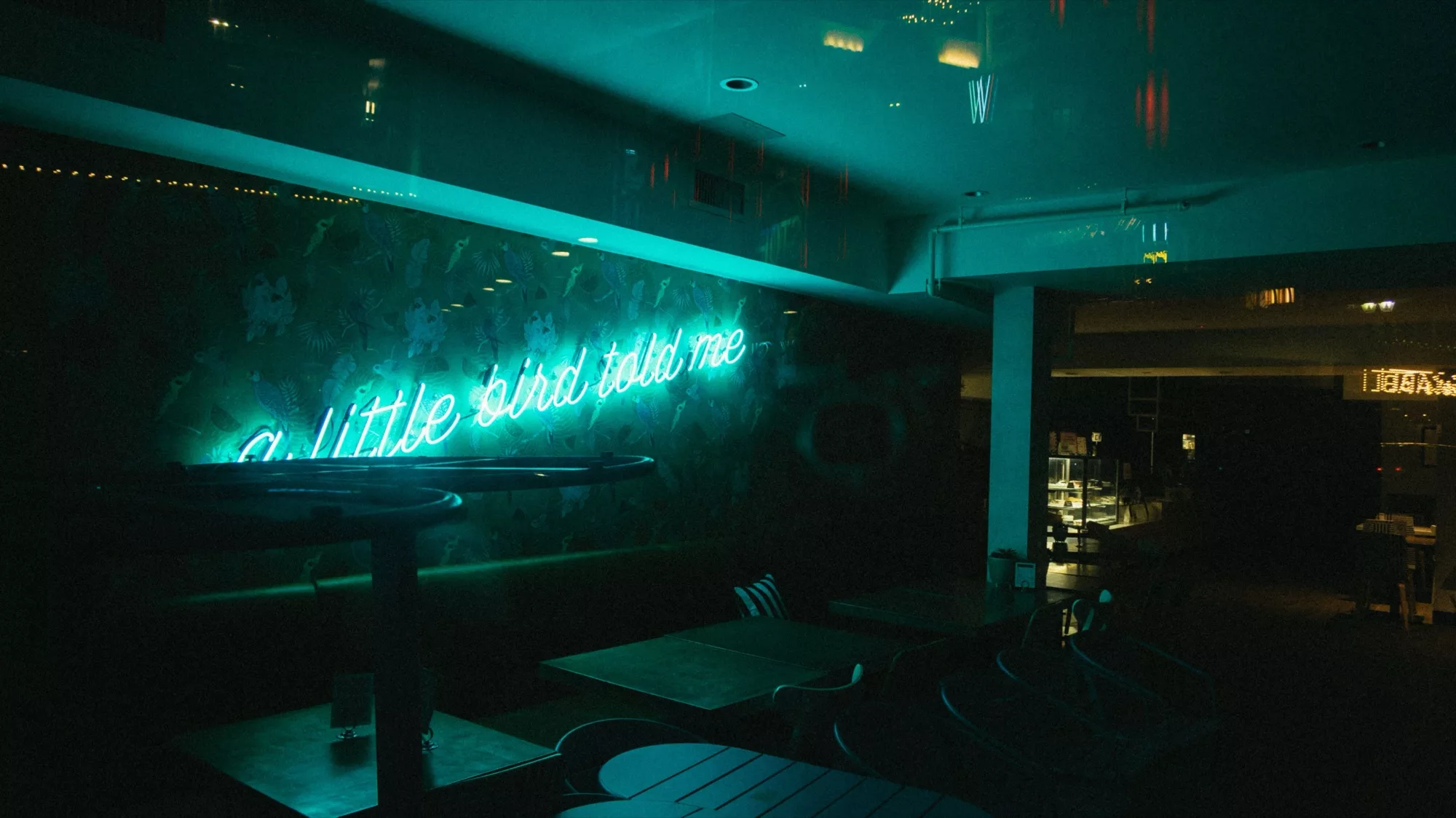 Neon Open sign glowing in the window of a dimly lit lounge at night