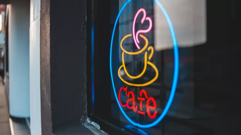 neon cafe sign glowing in a coffee shop window